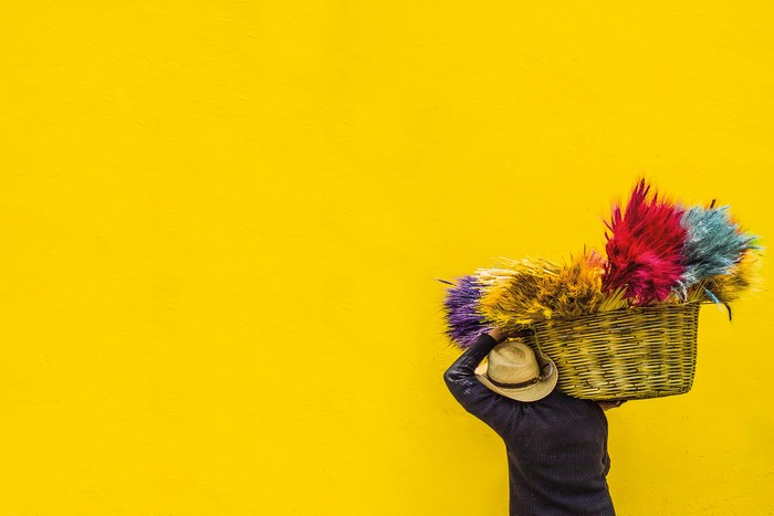 Man carrying a basket of colorful dyed grass on his head