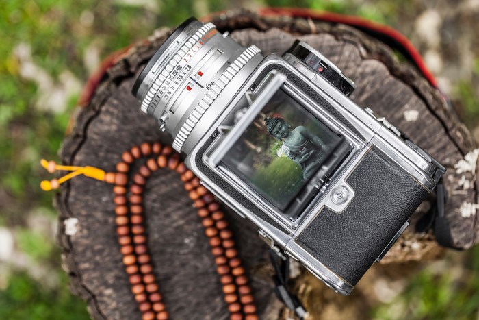 Hasselblad camera with Buddha statue reflection and mala beads