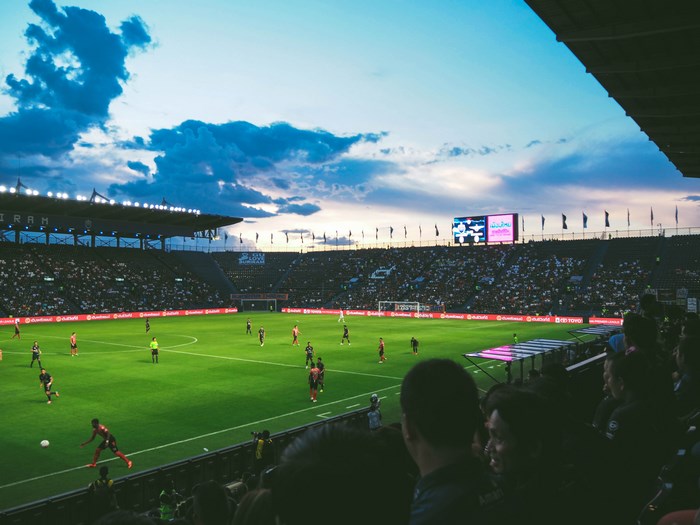 Football stadium with players and crowd at dusk