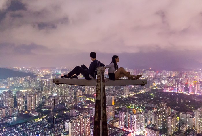 Couple sits on a crane overlooking Shenzhen at night