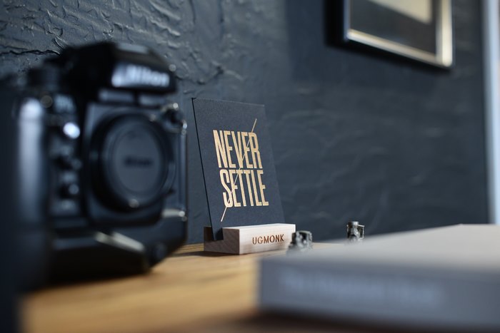 Nikon camera and "Never Settle" quote on a desk