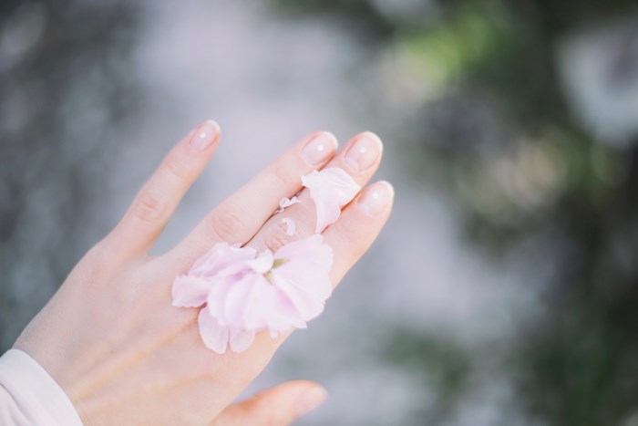 Woman's hand with pink flower petals and manicure