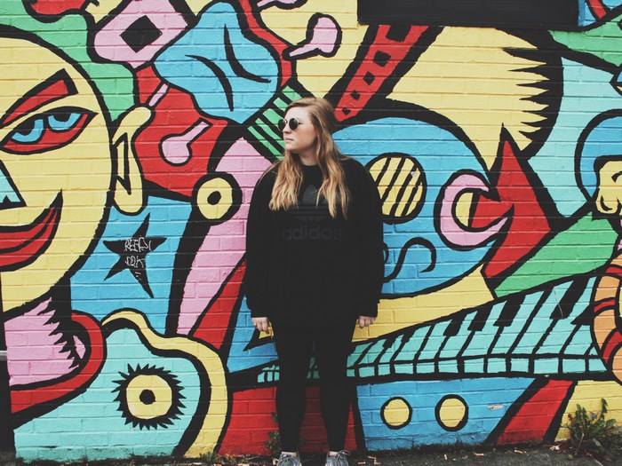 Woman standing in front of colorful graffiti mural