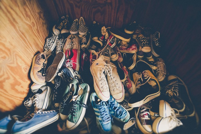 A pile of Converse shoes in a wooden bin
