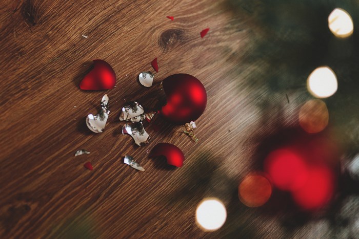 Broken red Christmas baubles on a wooden floor