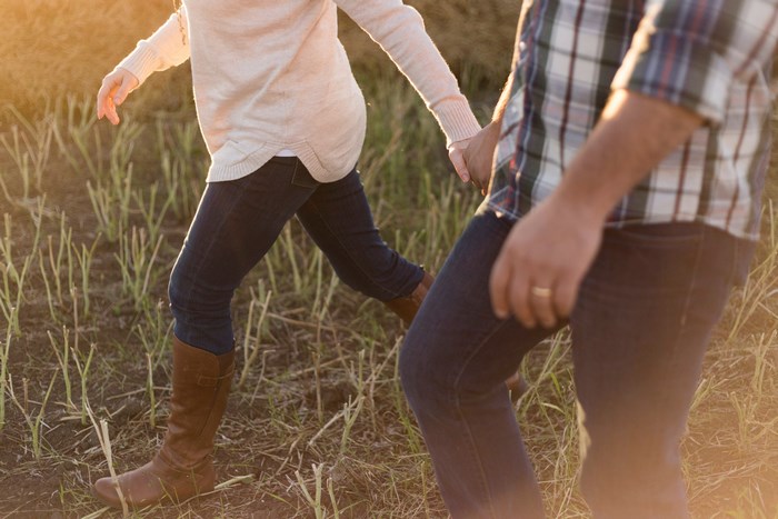 Couple holding hands walking in a field