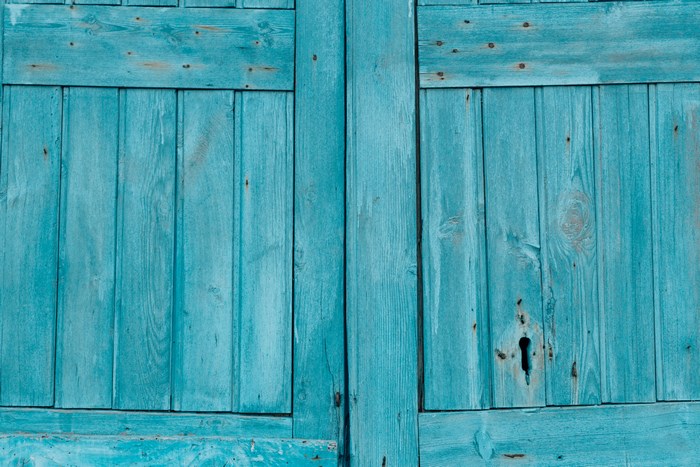 Close up of weathered blue wooden door with keyhole