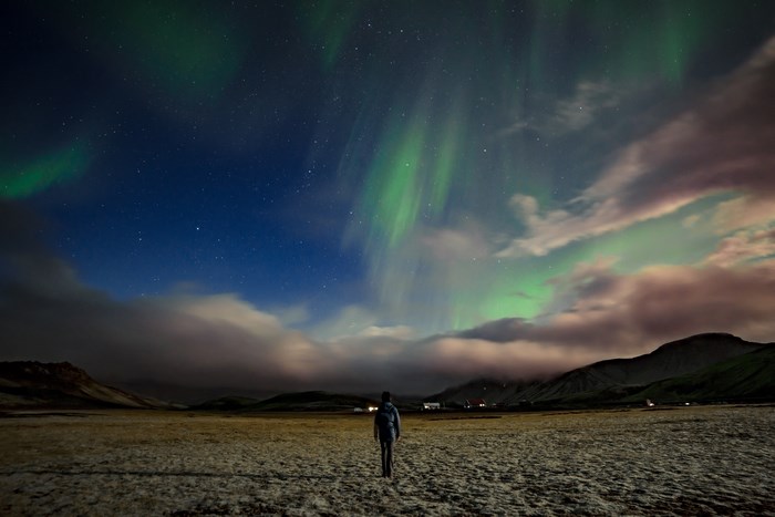Person watching Aurora Borealis over a landscape