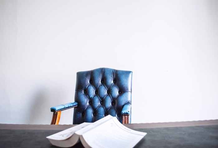 Blue tufted chair and open book on a desk