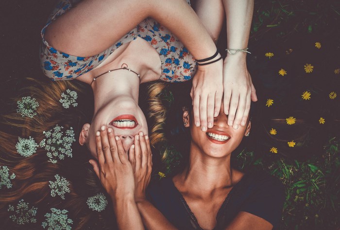 Two women lying down with hands covering eyes