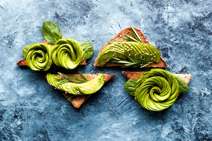 Avocado toast with spinach and rosemary on a blue textured background