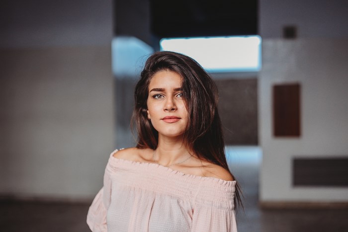 Beautiful woman with brown hair in a pink off-the-shoulder top