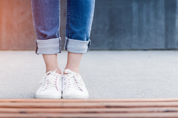 Woman wearing jeans and white canvas shoes