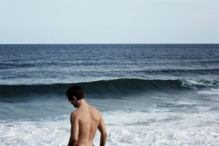 Shirtless Young Man Standing by Ocean Waves