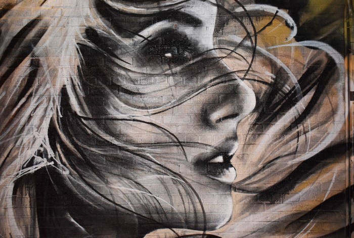 Graffiti of a woman's face on a brick wall in Brooklyn