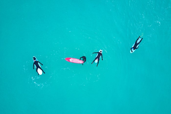 Surfers in wetsuits floating on surfboards in turquoise water
