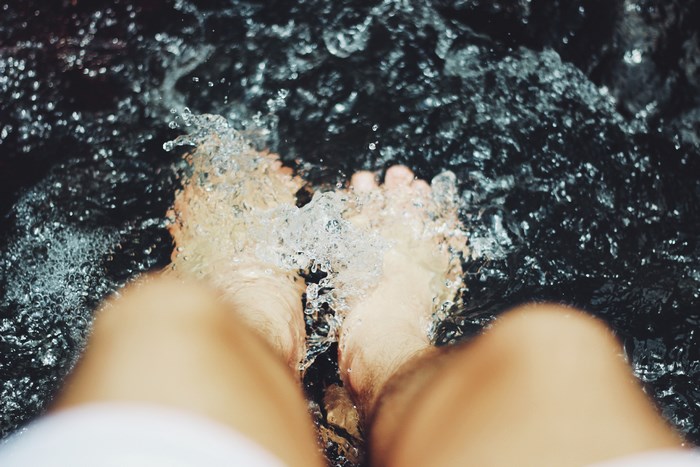 Person's feet splashing in dark water
