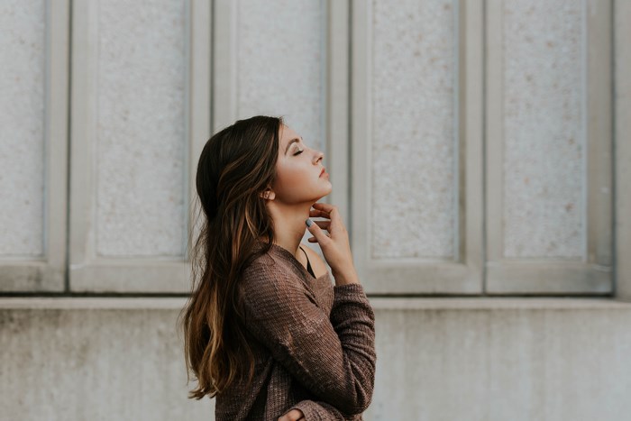 Woman with eyes closed touching her neck