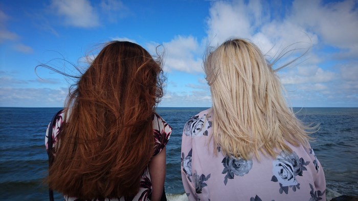 Two women with windblown hair by the sea