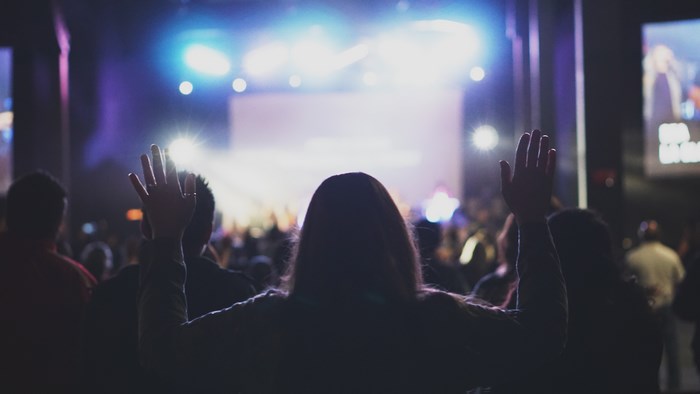 People with hands raised at a concert or worship service