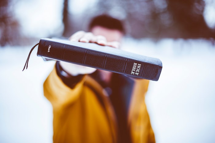 Man holding a Holy Bible in the snow