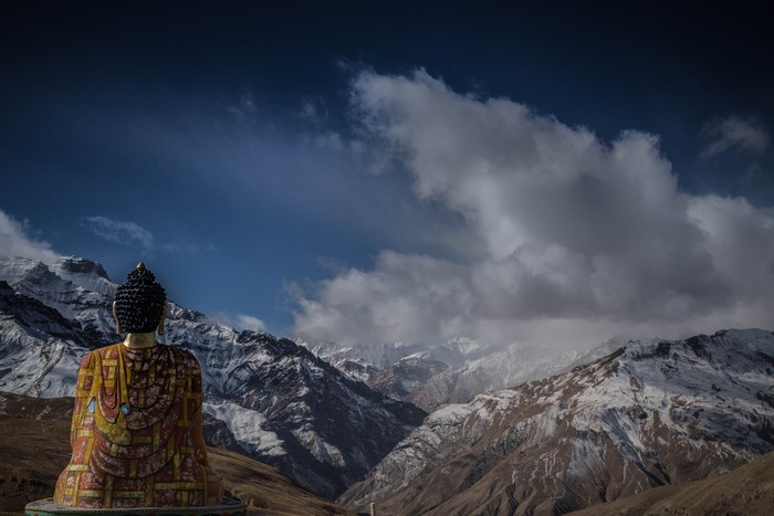 Buddha statue overlooking snow-capped mountains