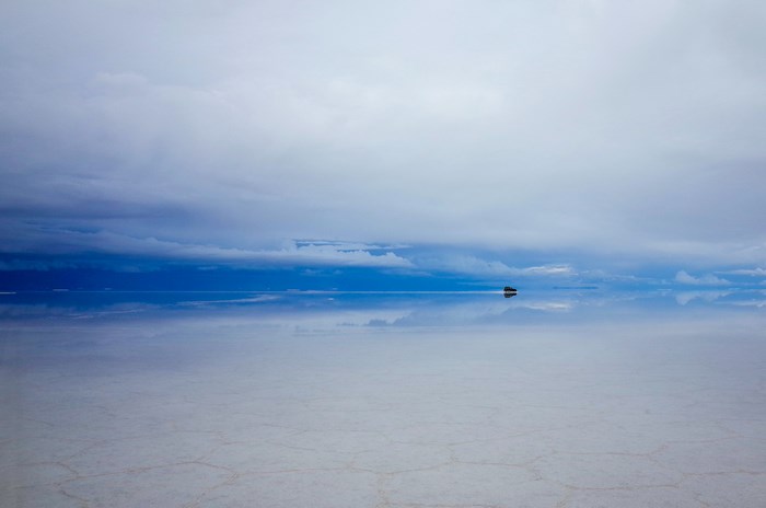 Salar de Uyuni salt flat with a car and reflection