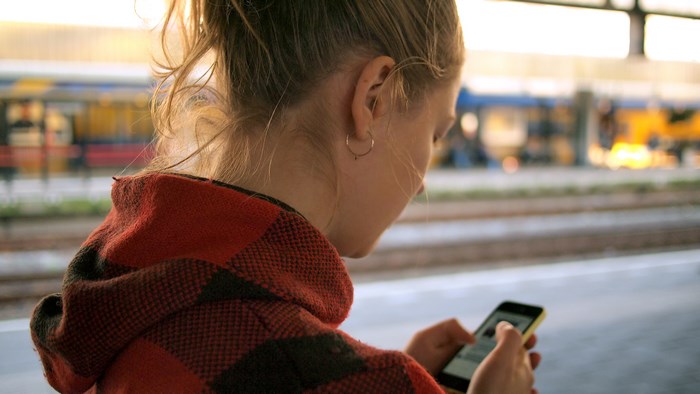 Woman Using Smartphone at Train Station Platform