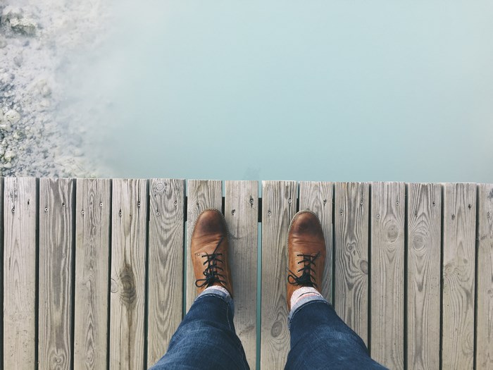 Feet on a wooden boardwalk overlooking a blue lagoon
