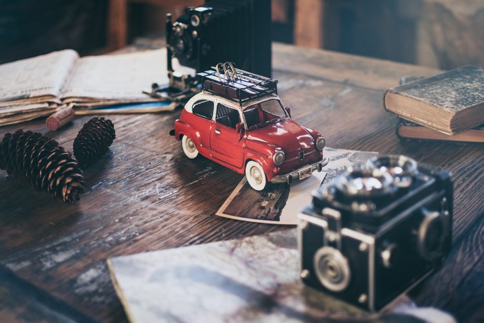 Vintage camera, red car, and books on a wooden table