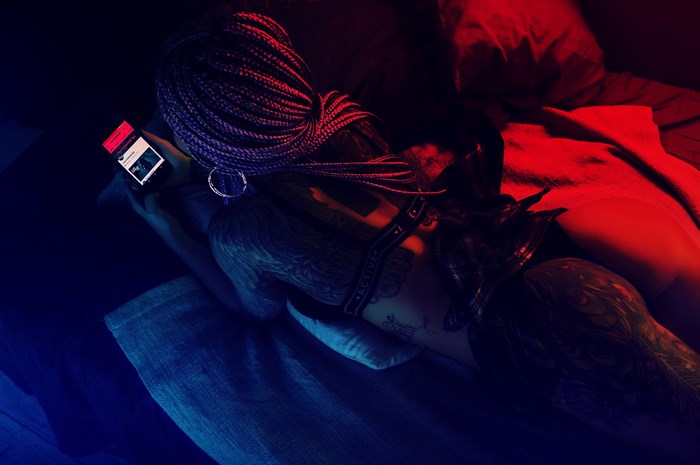 Woman with tattoos using a mobile phone in neon light