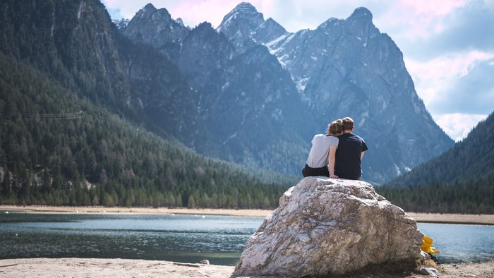 Couple sitting on a rock overlooking a mountain lake