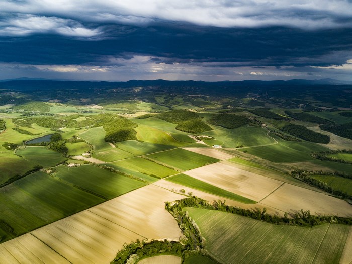 Aerial view of rolling green hills and fields under a cloudy sky