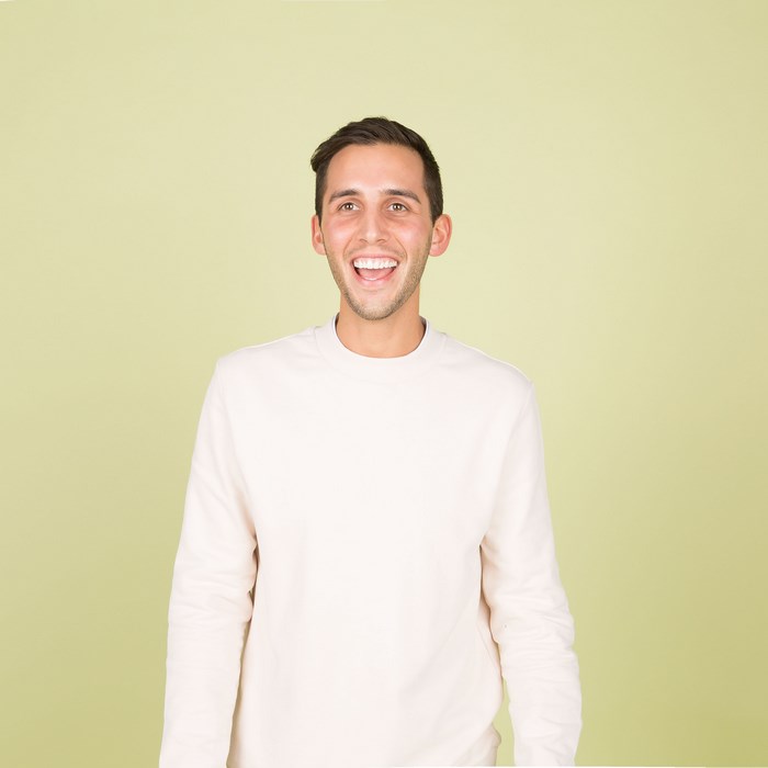 Young man with stubble smiling in a cream jumper