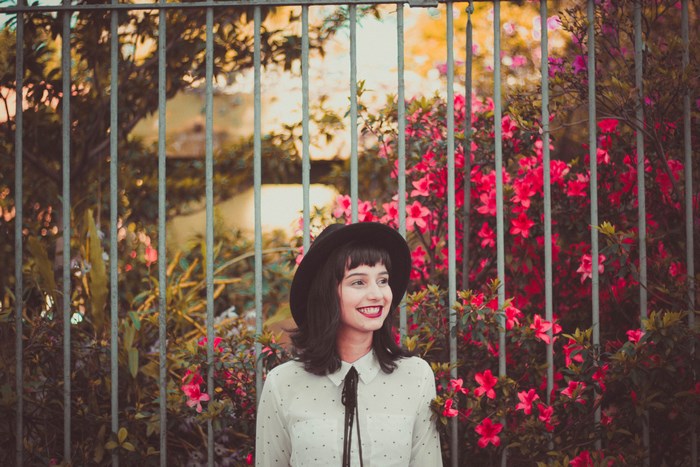 Woman in a hat and polka dot shirt behind a fence