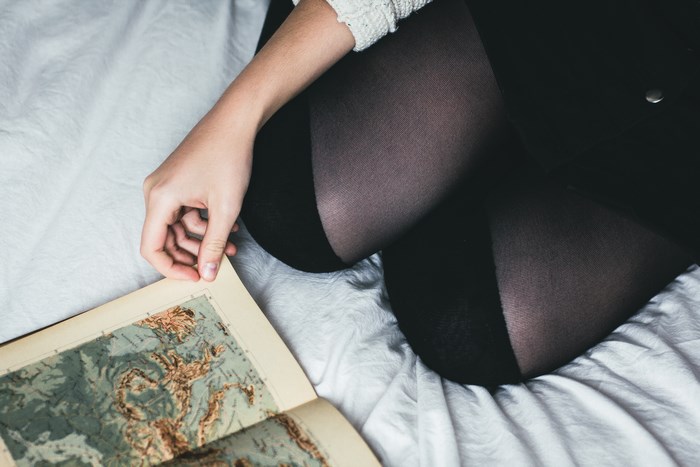 Woman Reading a Vintage Map on Bed