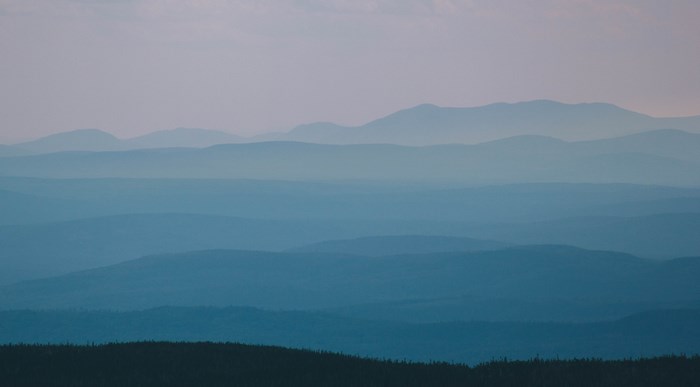 Layered blue mountains under a pastel sky