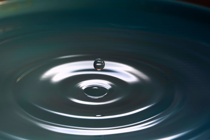Water droplet falling into rippling water