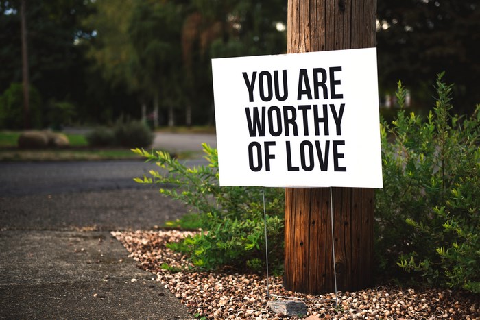 Sign that says "You Are Worthy Of Love" on a pole