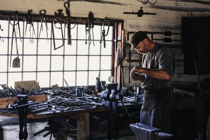 Blacksmith working in a cluttered workshop with tools