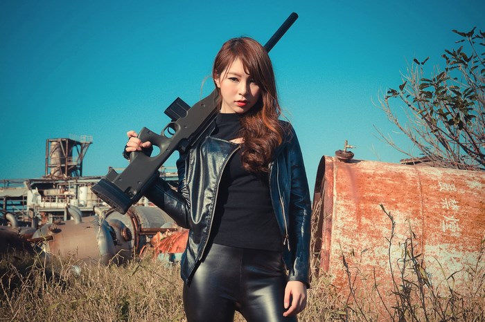 Woman with sniper rifle in industrial area
