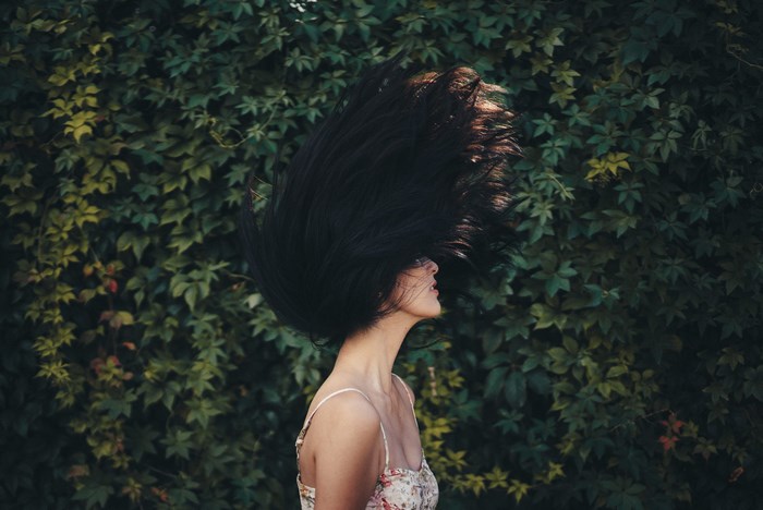 Woman with hair flip in front of green foliage