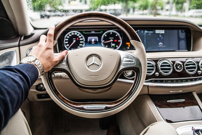Mercedes-Benz luxury car interior with driver's hand on steering wheel