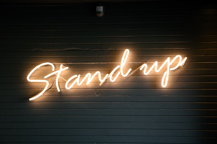Illuminated neon sign that says "Stand up"