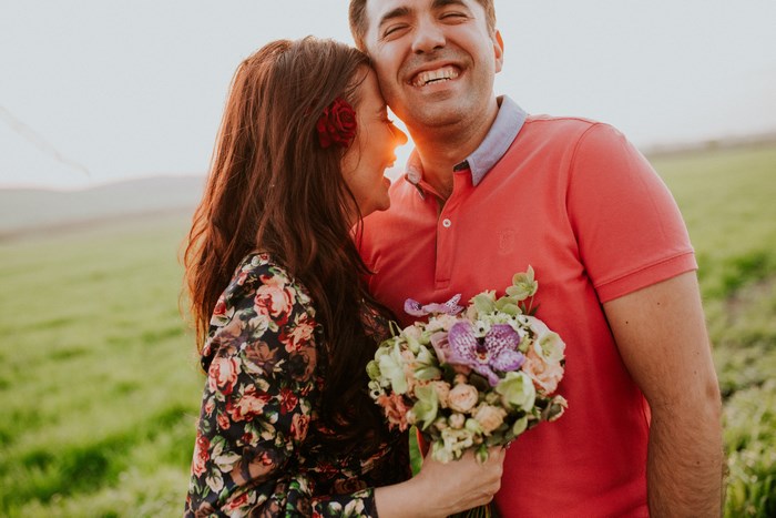 Couple laughing outdoors with a bouquet