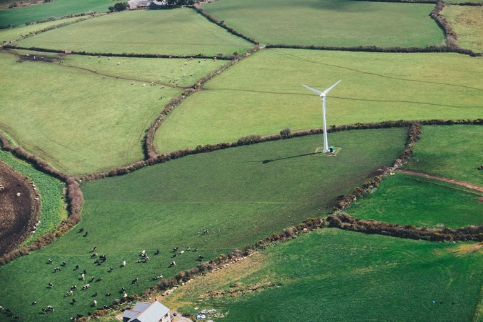 Aerial view of a farm with a wind turbine and cattle