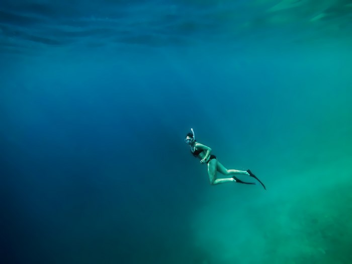 Woman Snorkeling Underwater in Clear Blue Sea