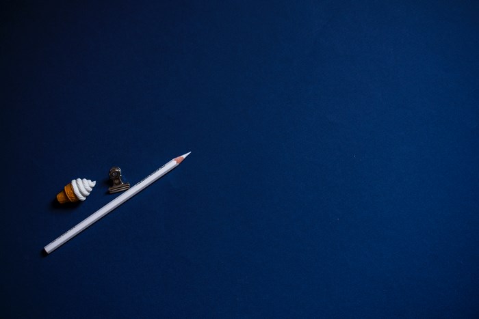 Minimalist white pencil and clip on blue surface