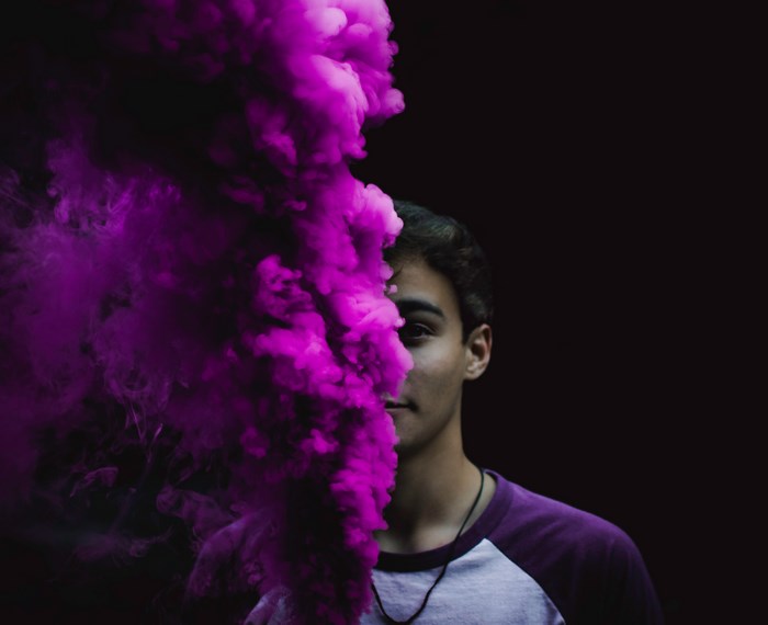 Man partially obscured by purple smoke grenade