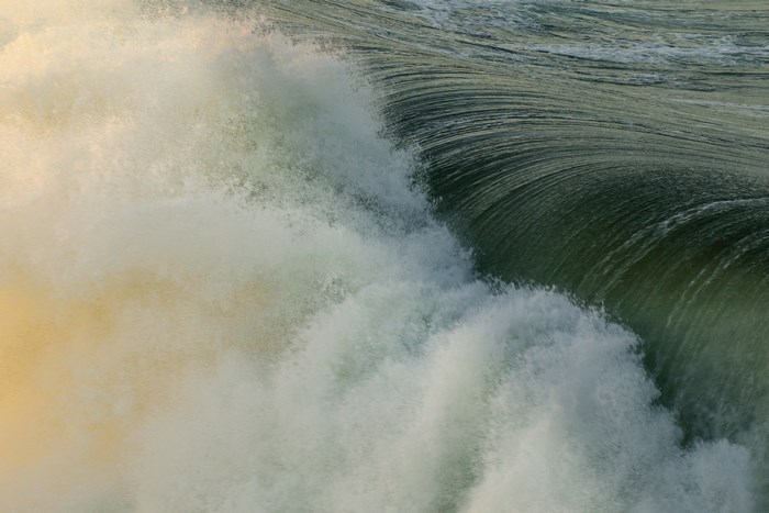 Close-up of a rough ocean wave with foam and sunlight